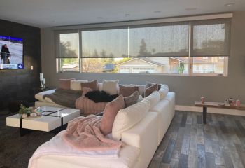 Chula Vista living room with custom sheer roller shades partially lowered over wide windows, diffusing sunlight for a cozy and modern atmosphere.