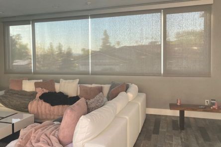 Contemporary Chula Vista living room with a white sectional and custom window shades, showcasing elegant, filtered natural light.