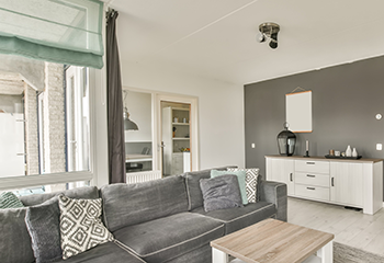 A modern living room adorned with elegant green Roman shades and grey drapery.